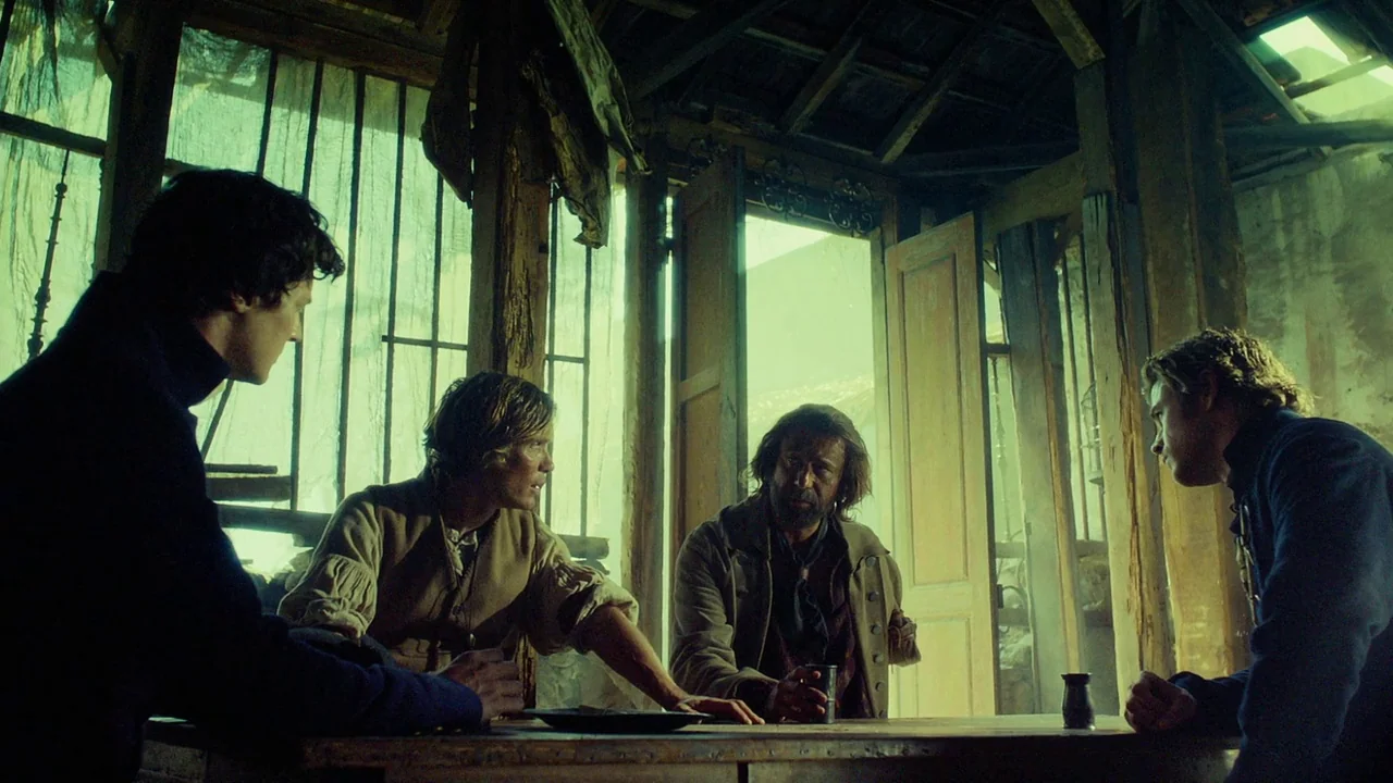 In The Heart of the Sea (2014) movie still: medium — A dilapidated, weathered timber room shows signs of age with exposed wood beams. Four men sit…