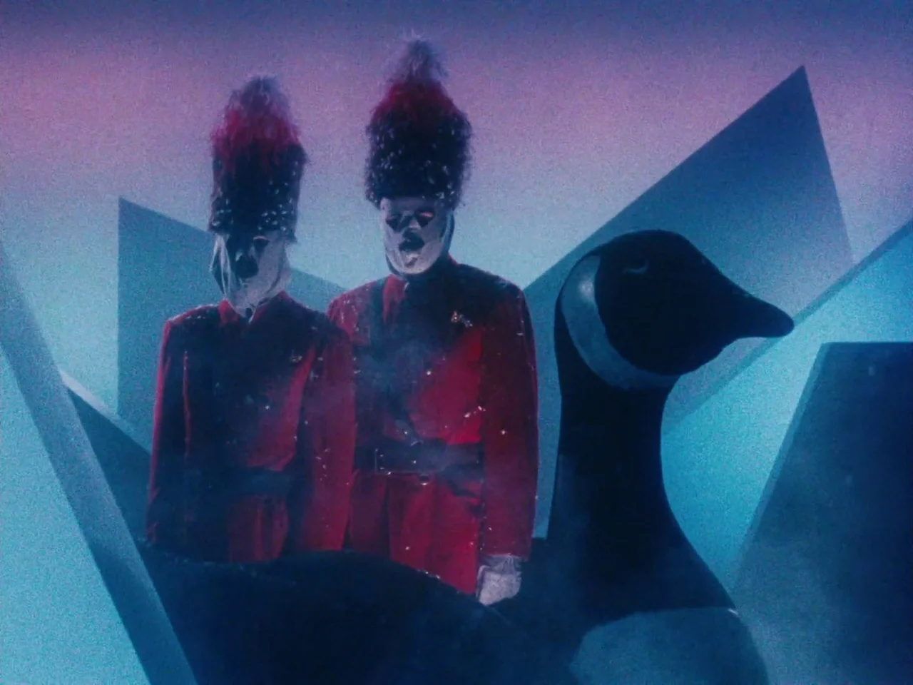 The Twentieth Century (2019) movie still: medium — A stylized studio set features dark geometric shapes under a deep blue wash of light. Two men…
