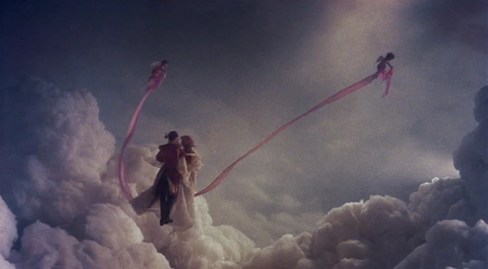 The Adventures Of Baron Munchausen (1988) movie still: wide — A couple floats above dense, billowy white clouds under a soft, overcast sky. They are…