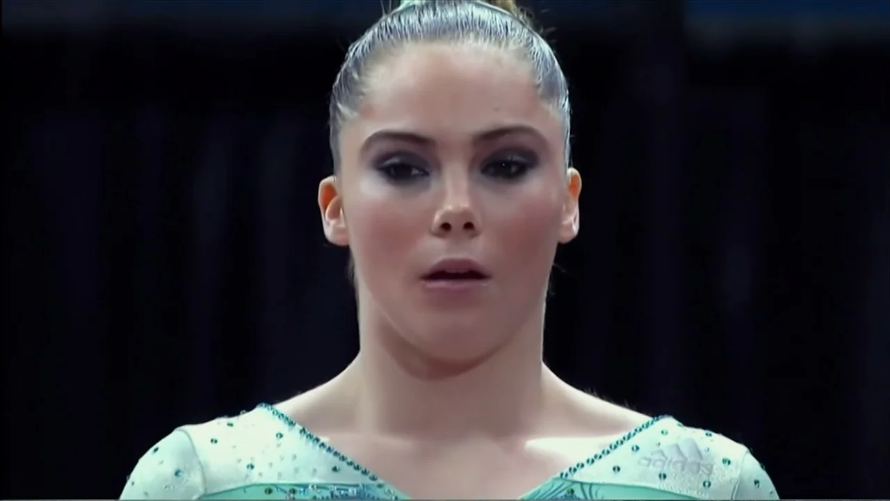 At the Heart of Gold: Inside the USA Gymnastics Scandal (2019) movie still: closeup — A high-intensity gymnastics arena with a dark curtain…