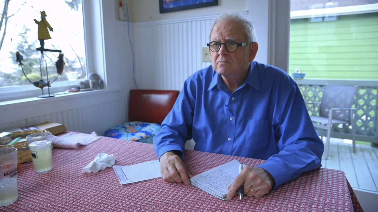 Moonlight Sonata: Deafness in Three Movements (2019) movie still: medium — A sunroom with a table covered by a red patterned tablecloth. An elderly…