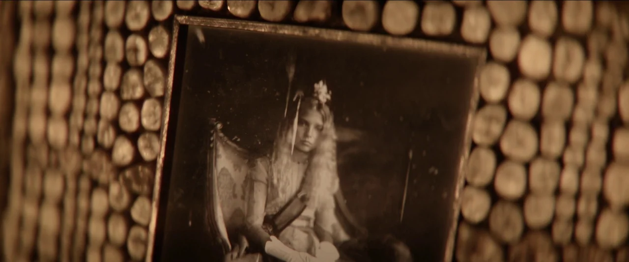 Rebel Moon – Part One: A Child of Fire (2023) movie still: closeup — A close-up of a vintage photograph encased in a heavy wooden frame decorated…