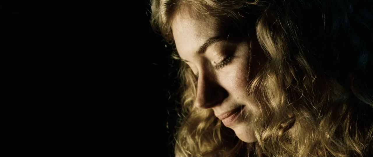 Centurion (2010) movie still: closeup — A dark, nondescript interior space features no visible architectural details. A young woman with blonde hair…