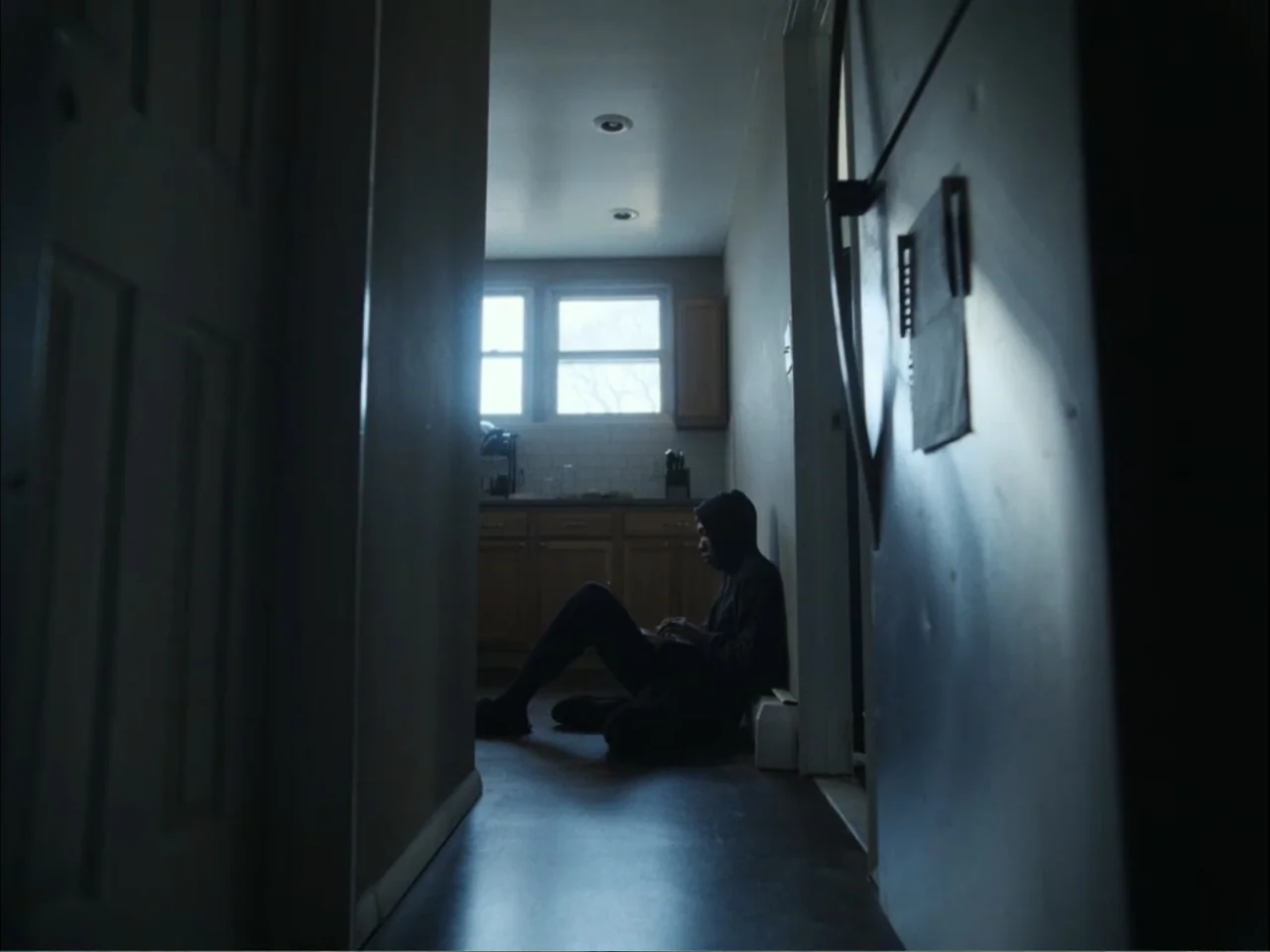 As We Speak: Rap Music on Trial (2024) movie still: medium — A dark corridor leads to a brightly lit room featuring wooden cabinets and windows. A…