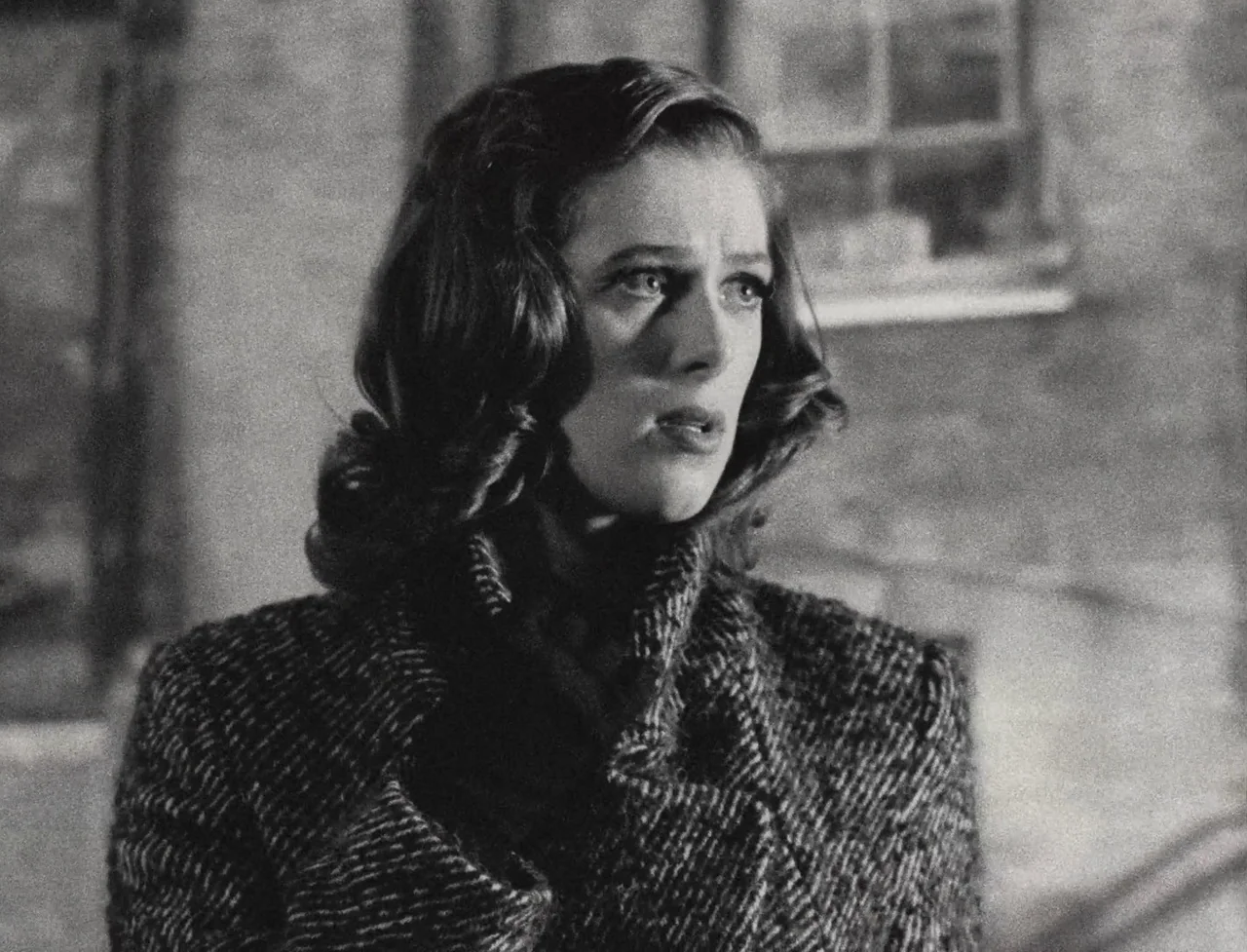 The Souvenir: Part II (2021) movie still: medium — A woman stands on a dark city street with blurred masonry in the background. She is looking…