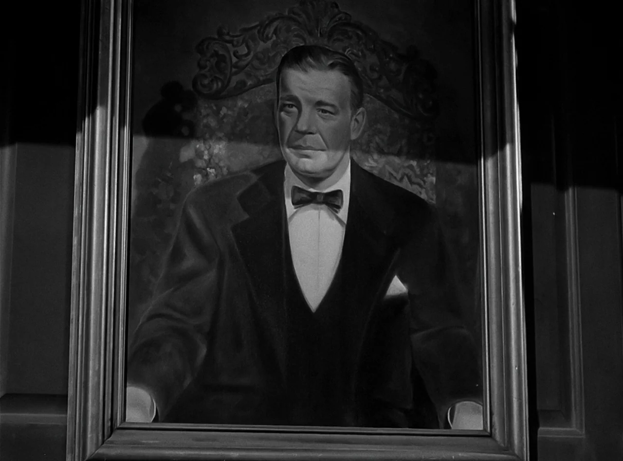 The Wolf Man (1941) movie still: closeup — A portrait of a man in a tuxedo is set in an ornate frame. The man looks directly ahead while seated in a…