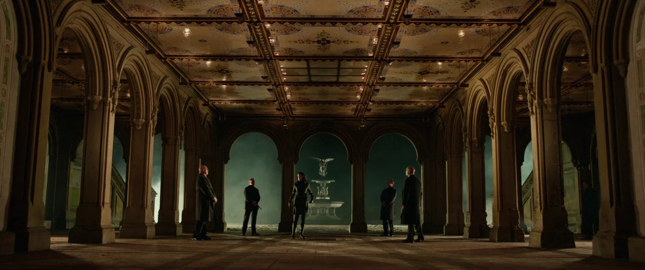 John Wick (2014) movie still: wide — A stone arcade with vaulted ceilings and patterned tiles forms a symmetrical open structure. Five figures stand…