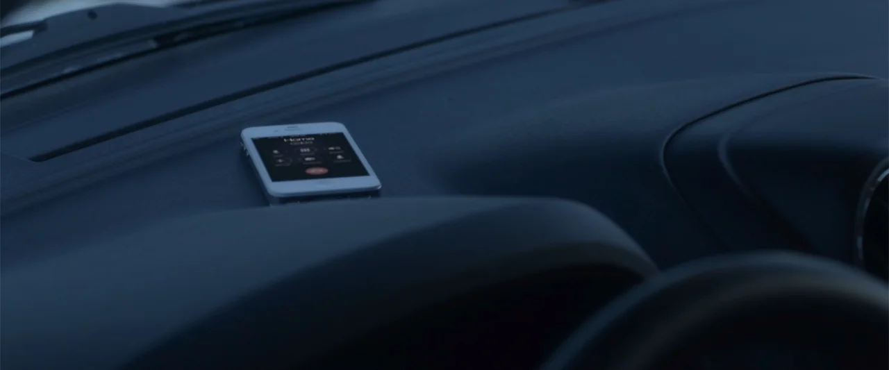 Radius (2017) movie still: closeup — A modern vehicle dashboard features dark plastic surfaces and a curved instrument panel area. A white…