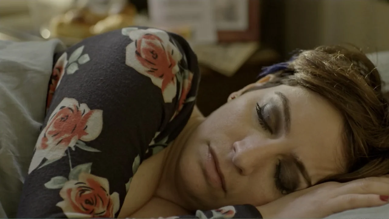 Heaven Sent (1994) movie still: closeup — A woman sleeps in a bed with soft pillows and muted lighting. She rests her head on her arm while wearing…