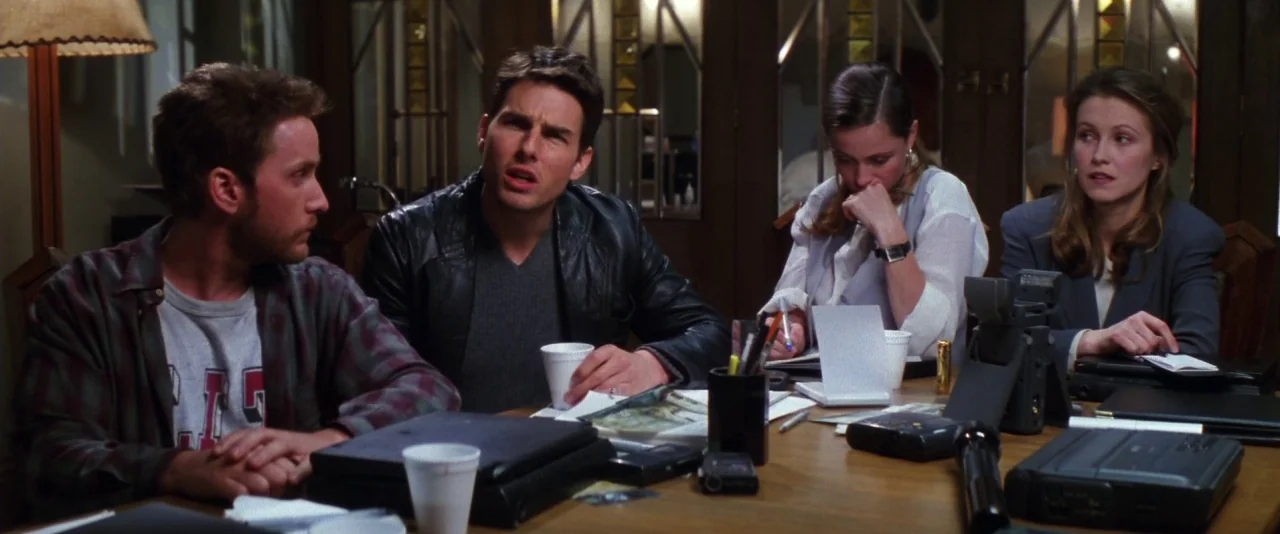 Mission: Impossible (1996) movie still: medium — A wooden table in a dimly lit conference room holds electronic recording equipment. Four…