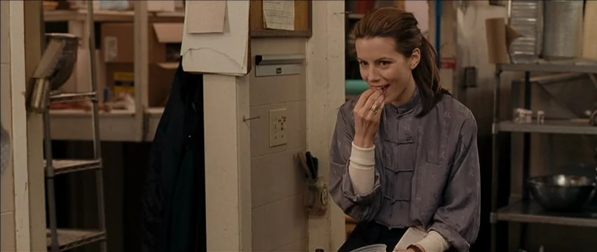 Snow Angels (2007) movie still: medium — A utilitarian food preparation area with metal shelving, tiled walls, and stacked supplies. A woman in a…