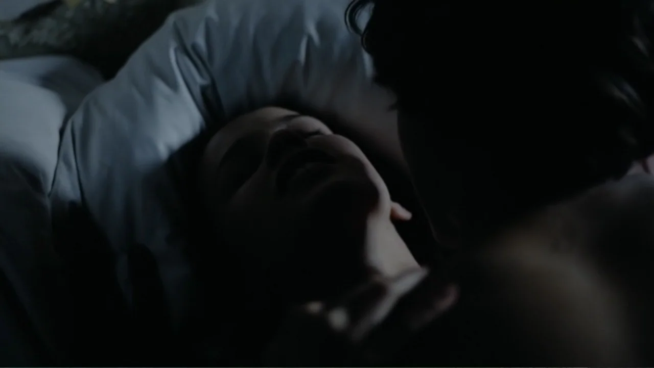 Christiane F. (1981) movie still: closeup — A dark, dimly lit bedroom setting with soft, shadowed surfaces on a bed. A person rests on a white…