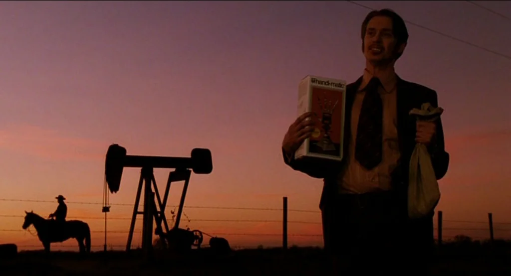 Big Fish (2003) movie still: medium — A man stands in an oil field at dusk with a pumping unit behind him. A lone rider on horseback is silhouetted…