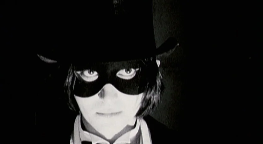 Brand Upon the Brain! (2006) movie still: closeup — A person wears a black top hat and a mask in total darkness. The subject stares straight ahead…
