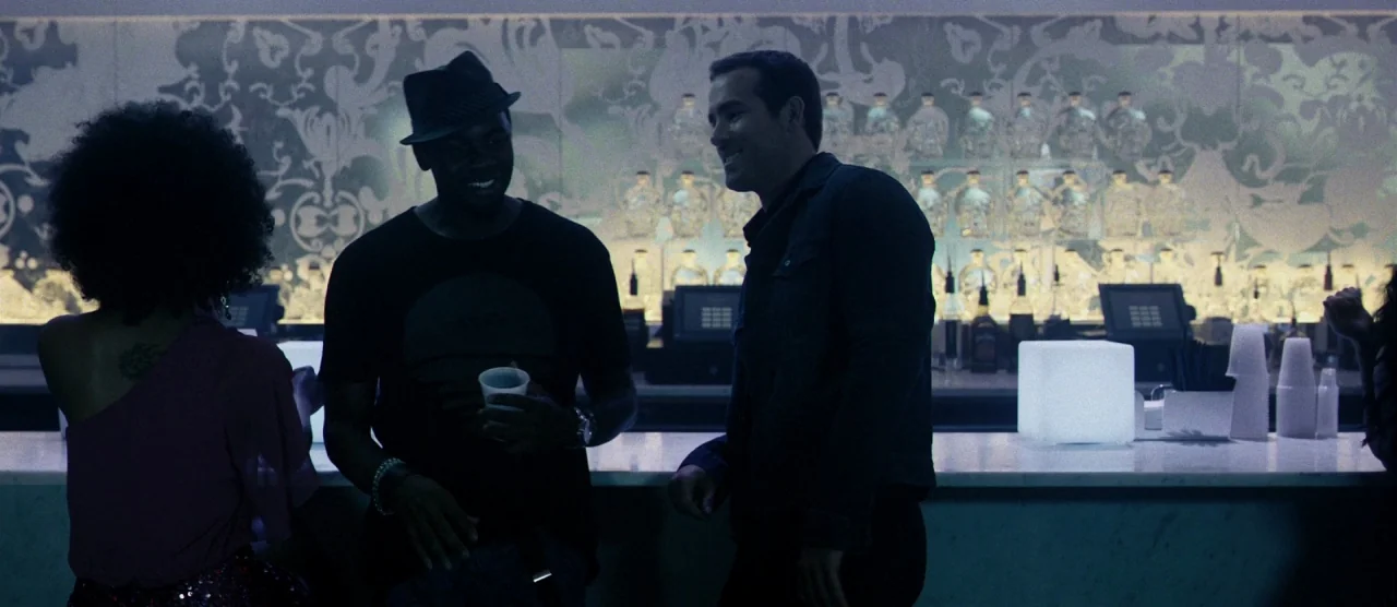 Self/less (2015) movie still: medium — A modern bar features a long white marble counter and glowing light cube decor. Three people converse while…