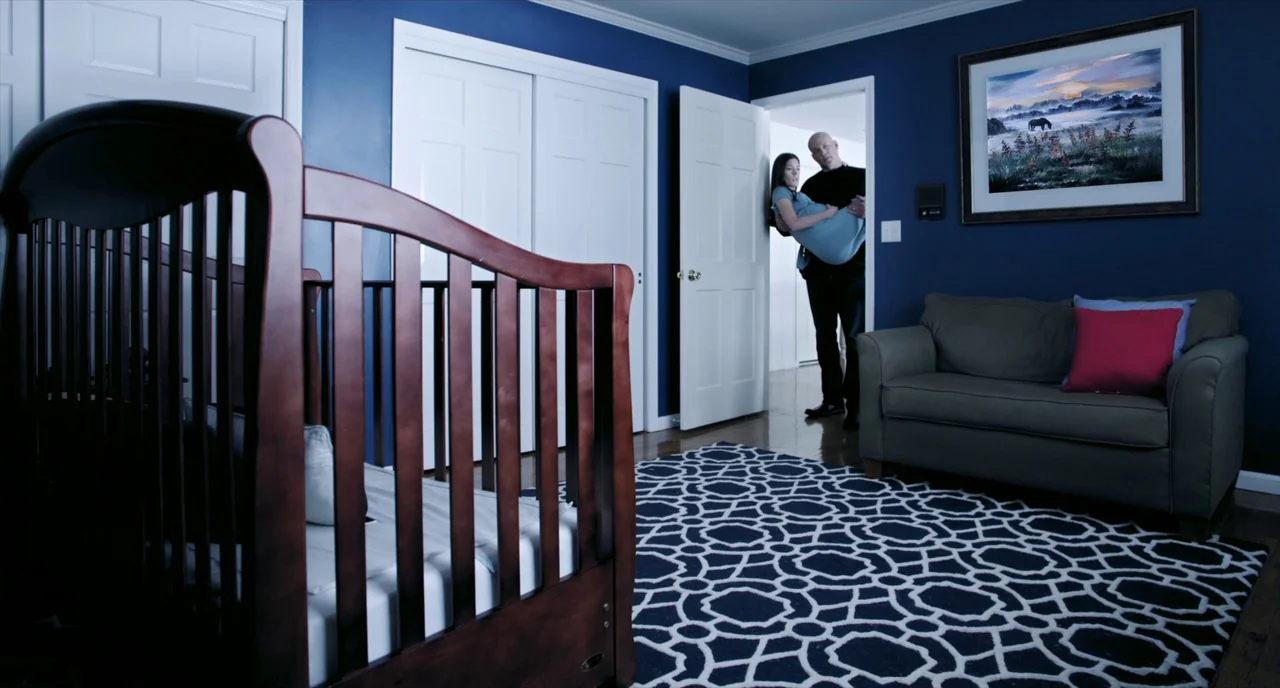 Brawl in Cell Block 99 (2017) movie still: wide — A dark blue room contains a wooden crib and a couch on a patterned rug. A bald man enters the…