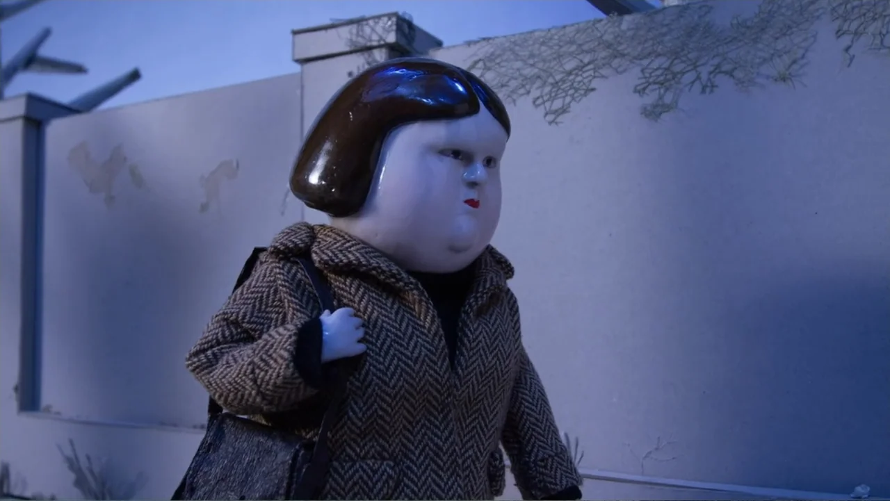 Bestia (2017) movie still: medium — A pale, stop-motion figure walks along a smooth grey concrete wall at night. The character moves along the wall…