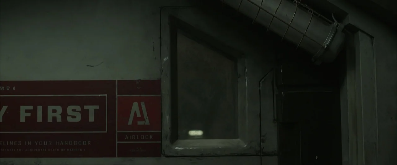 DISTANT (2026) movie still: establishing — An industrial wall surface features a red safety sign and a heavy airlock window. The metallic structure…