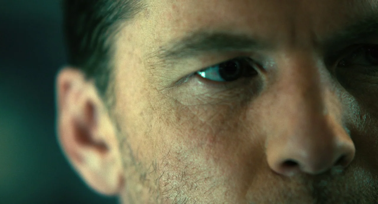 The Killer (2024) (2024) movie still: closeup — A close-up shot of a man's face in a dark, indistinct environment. The man is looking off-camera…