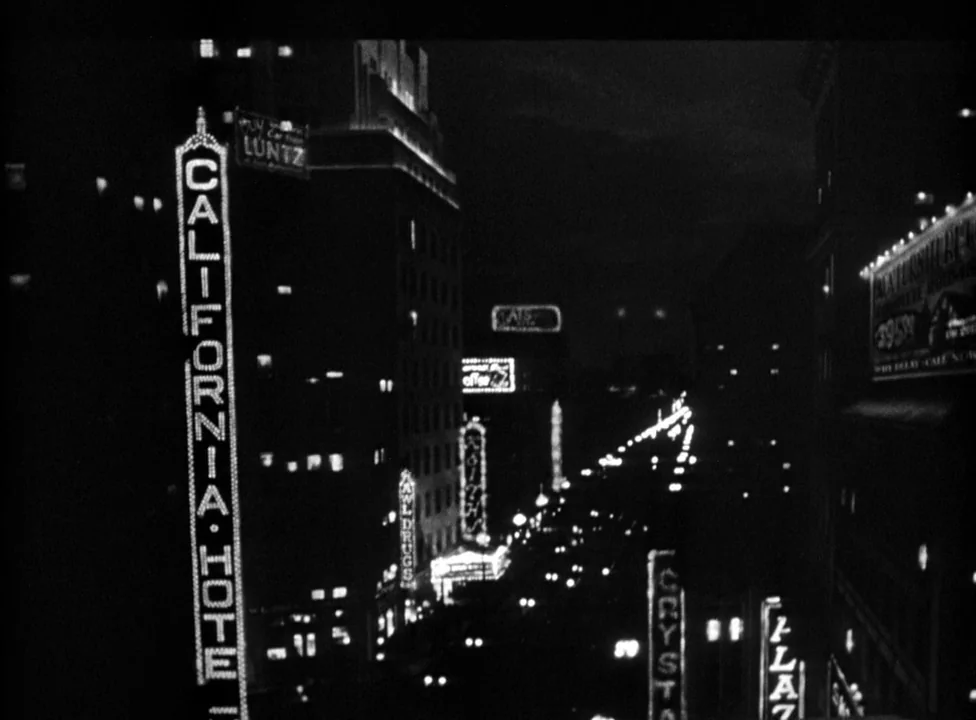 Murder, My Sweet (1944) movie still: establishing — A dark urban intersection is illuminated by several vertical glowing neon hotel signs. The frame…
