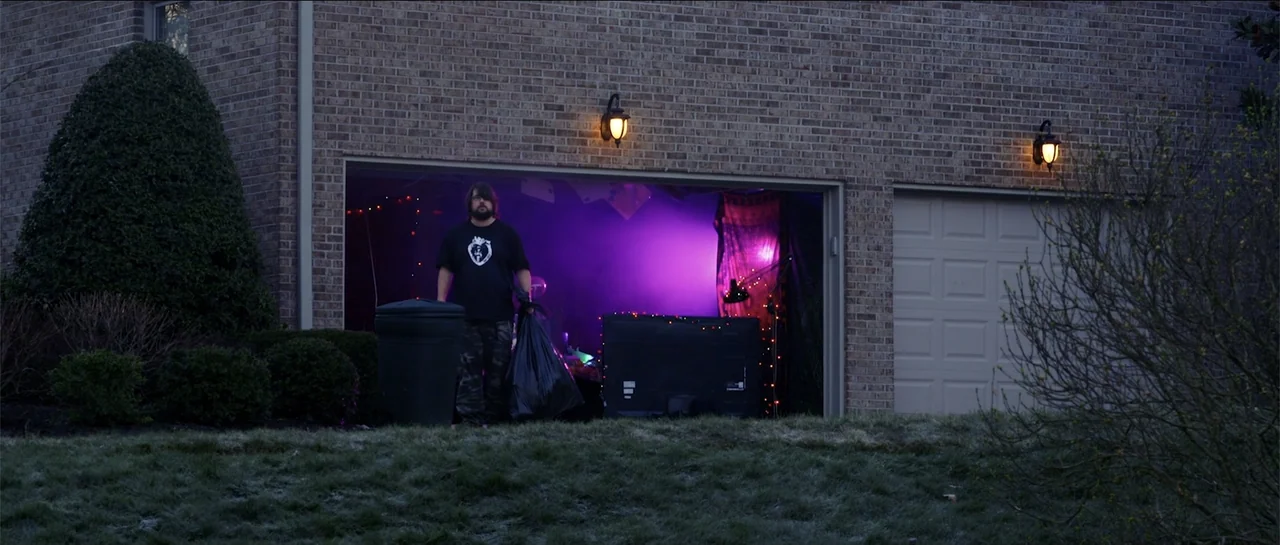 Halloween III: Season of the Witch (1982) movie still: medium — A suburban brick house garage is illuminated by a deep purple light from within. A…