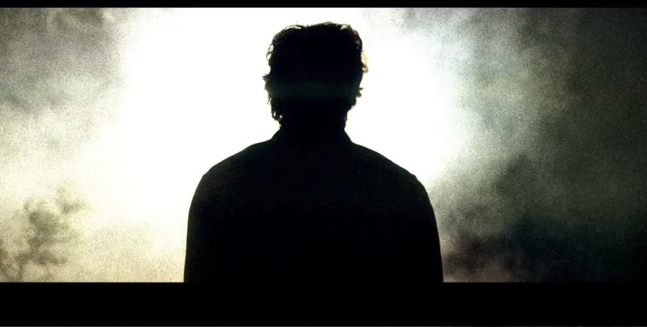 Alien Abduction: Travis Walton (2022) movie still: medium — An outdoor field filled with bright hazy light and diffuse textures. A man stands as a…