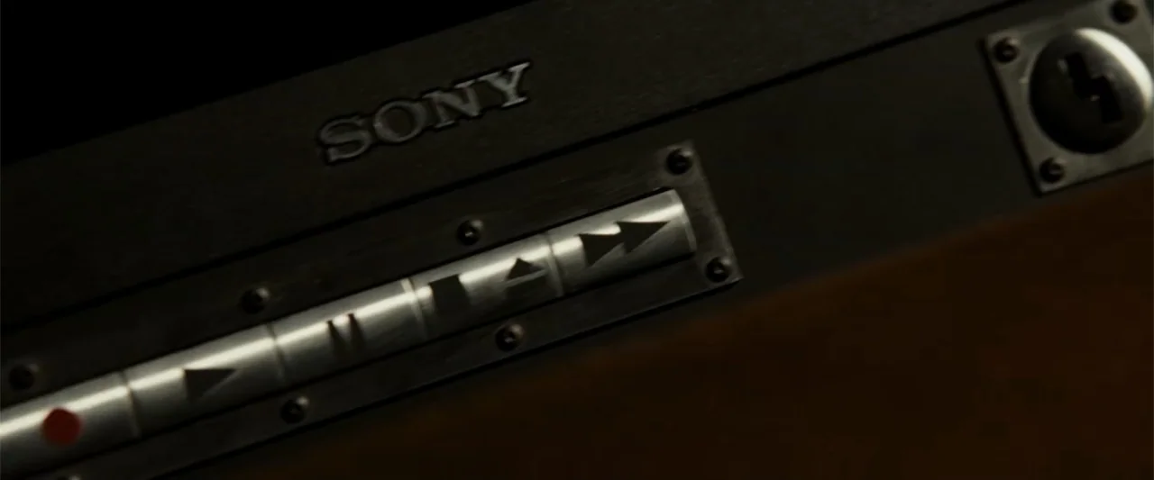 Angels & Demons (2009) movie still: closeup — A close-up of the control panel on a black vintage Sony electronic device. The metallic playback…