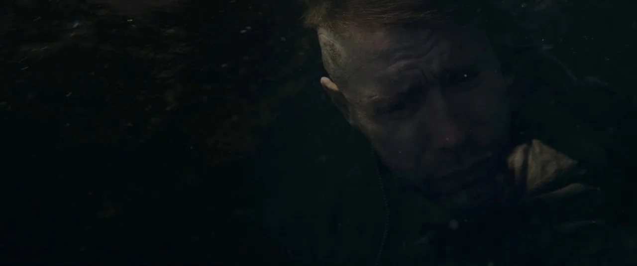 Journeyman (2017) movie still: closeup — A man is submerged underwater in deep, dark conditions with floating particles. He looks toward the surface…
