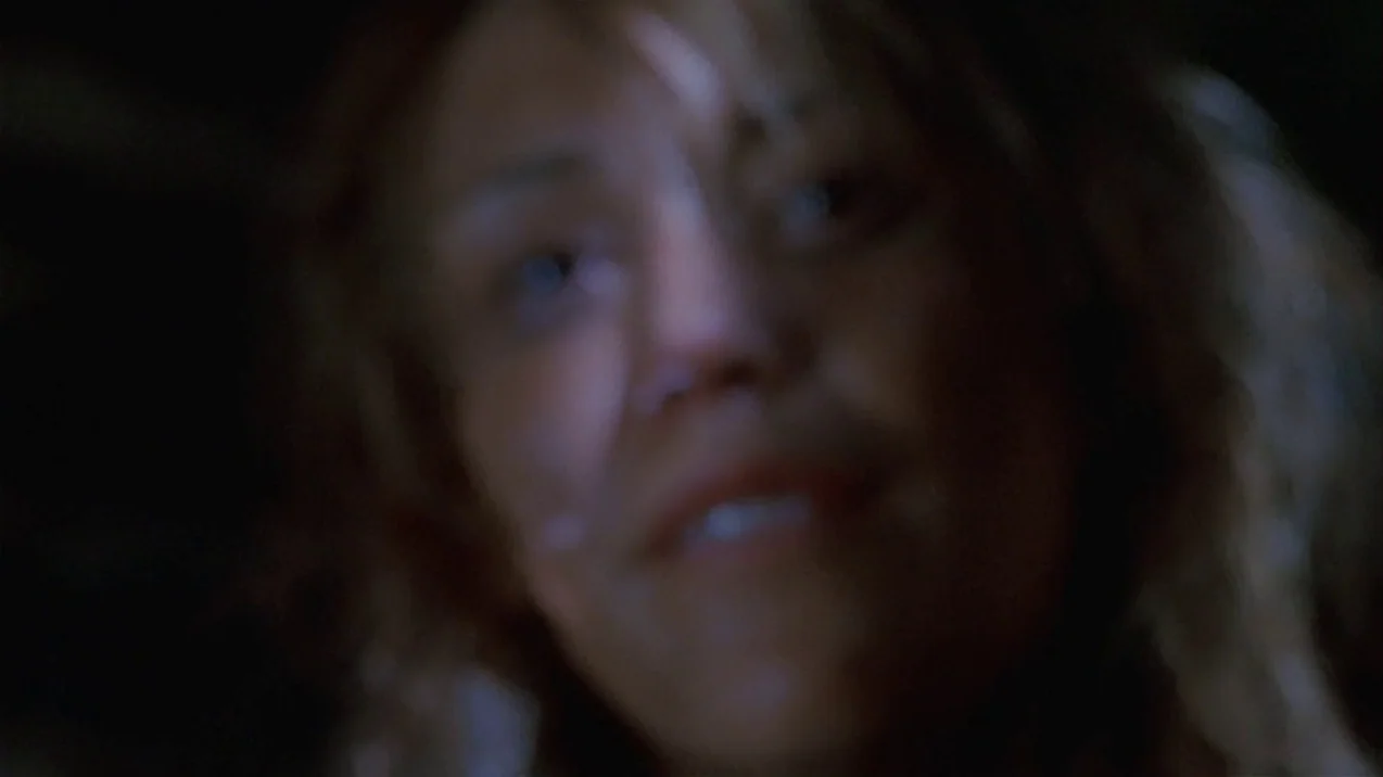 Dagon (2001) movie still: closeup — A dark, indistinct indoor location with minimal background features visible. A woman's face is positioned in the…