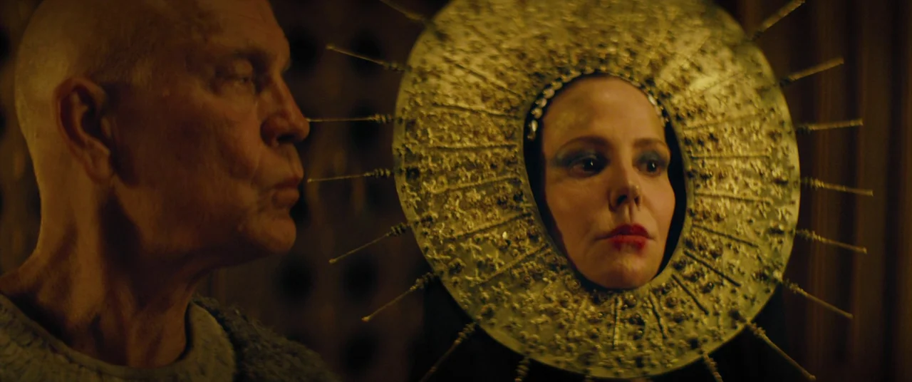 Seneca: On The Creation Of Earthquakes (2023) movie still: medium — A dark indoor space contains two people illuminated by a warm golden glow. A…