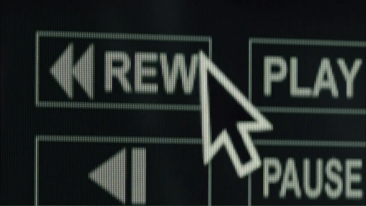Dark Skies (2013) movie still: closeup — A close-up view of a digital screen showing media playback control buttons with text. A white arrow cursor…
