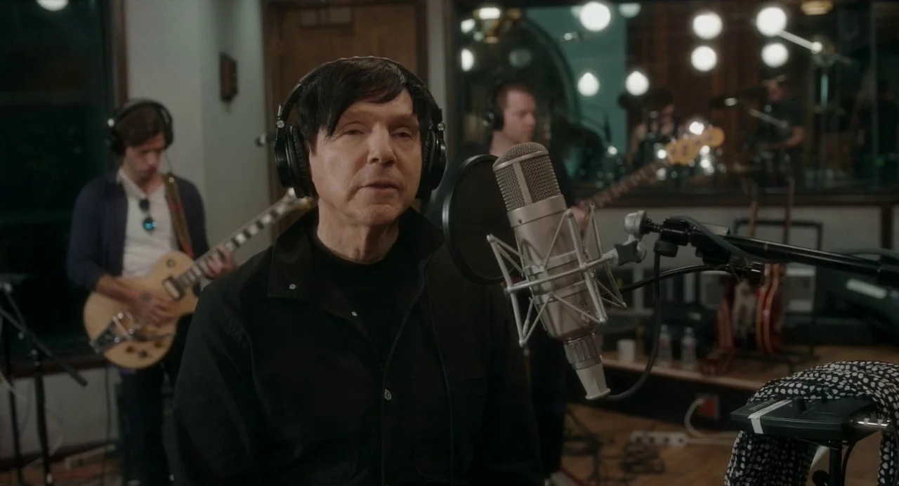 Annette (2021) movie still: medium — A professional recording studio features acoustic panels and glass dividers separating band members. The main…