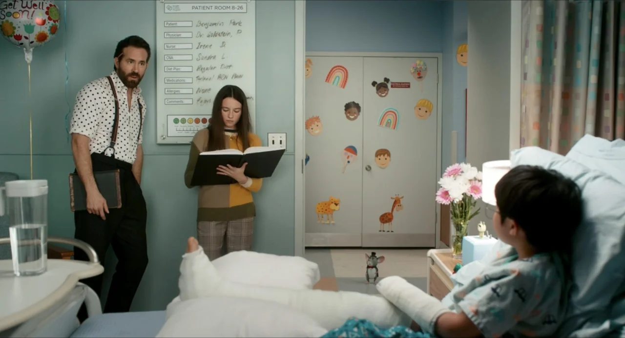 IF (2024) movie still: medium — A hospital room features light blue walls decorated with colorful paper animal cutouts. A man and a girl stand near…