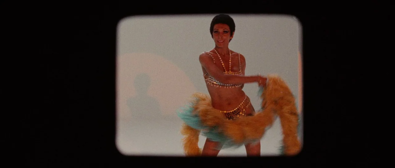 Death Walks On High Heels (1971) movie still: medium — A plain white studio cyclorama with soft even illumination and a faint shadow of the…