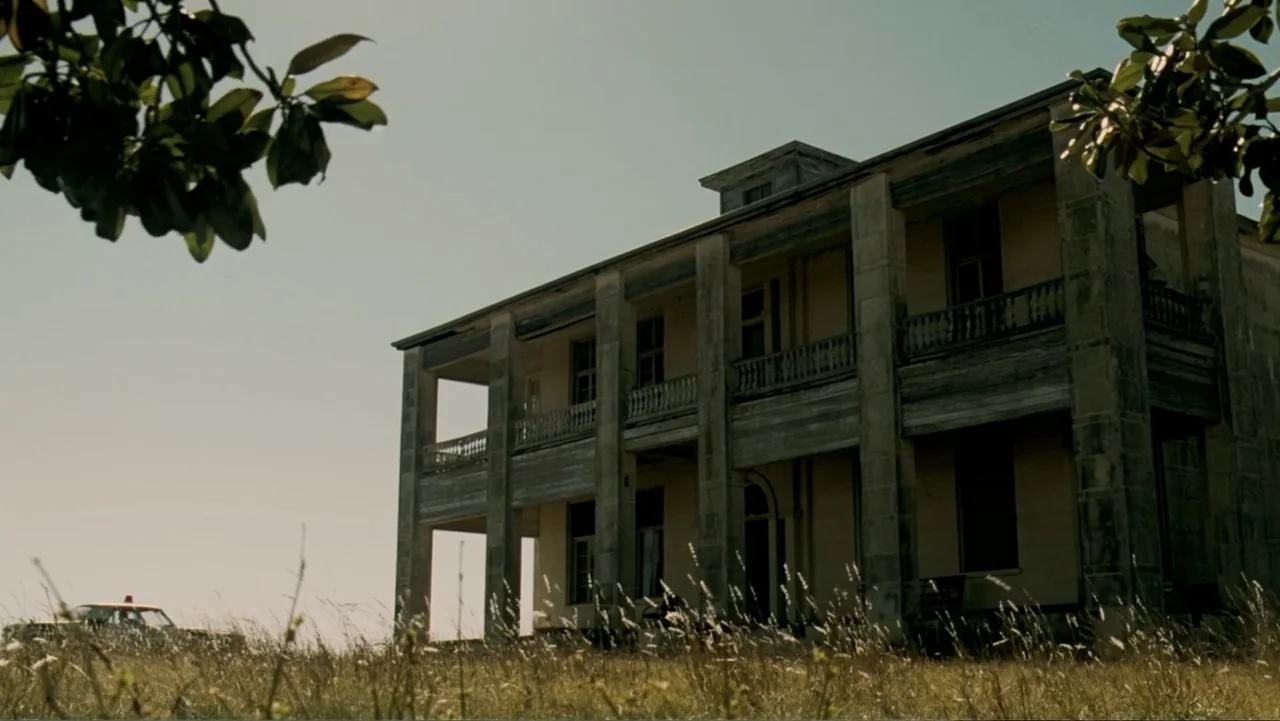 The Texas Chainsaw Massacre: The Beginning (2006) movie still: establishing — A weathered two-story colonial style mansion stands in a tall, dry…