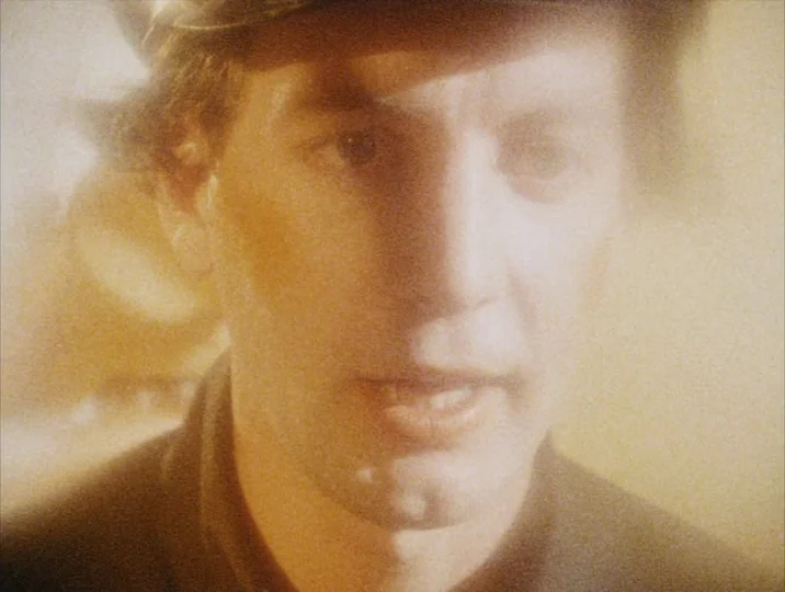 Careful (1992) movie still: closeup — A close-up shot captures a man's face bathed in soft, hazy, golden light. He is slightly angled and speaks to…
