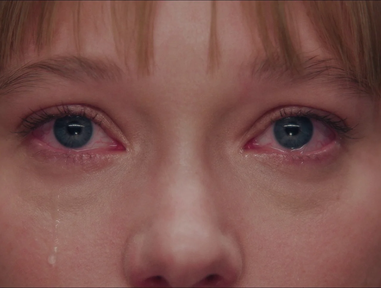Transformers: Rise of the Beasts (2023) movie still: closeup — An extreme close-up focuses on the upper portion of a young woman face. Tears fall…