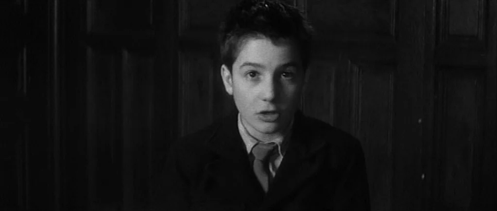 The 400 Blows (1959) movie still: medium — A dark, wood-paneled room provides a somber setting for the portrait. A young boy in a suit speaks while…
