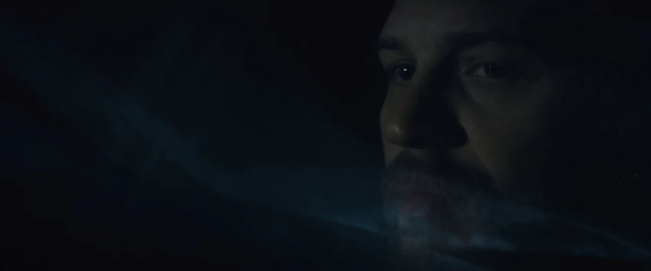 Locke (2013) movie still: closeup — A man's face is partially lit by the glow of a device in darkness. He stares intently at the unseen screen while…