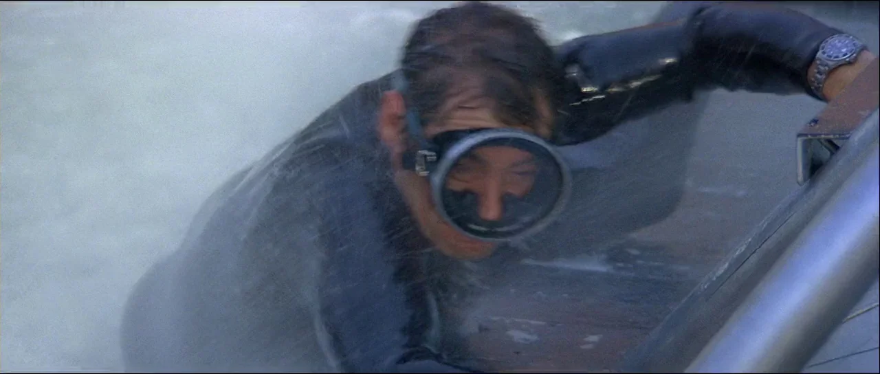 Licence to Kill (1989) movie still: closeup — A man in a wetsuit emerges from water onto the metal edge of a boat. He is pulling his body up while…