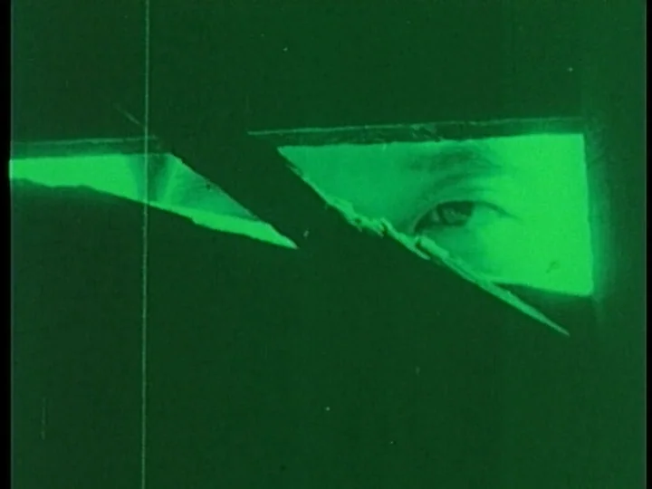 The Cage (1964) movie still: closeup — A dark, obstructed view shows only a human eye behind a wooden plank barrier. The scene is saturated with a…