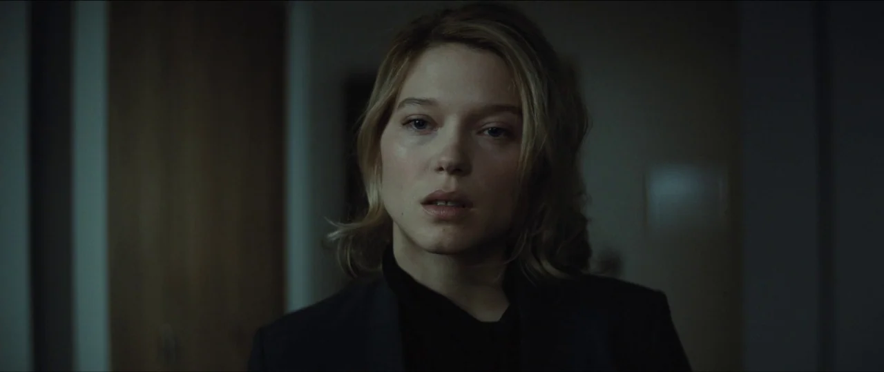 Spectre (2015) movie still: medium — A dimly lit room provides a dark, out-of-focus background for the subject. A woman looks forward while centered…