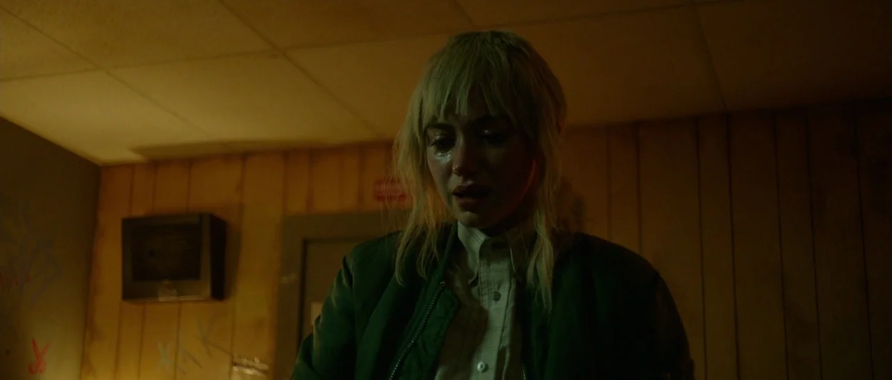 Green Room (2015) movie still: medium — A dimly lit room features wood-paneled walls with faint markings and a wall-mounted ventilation unit. A…