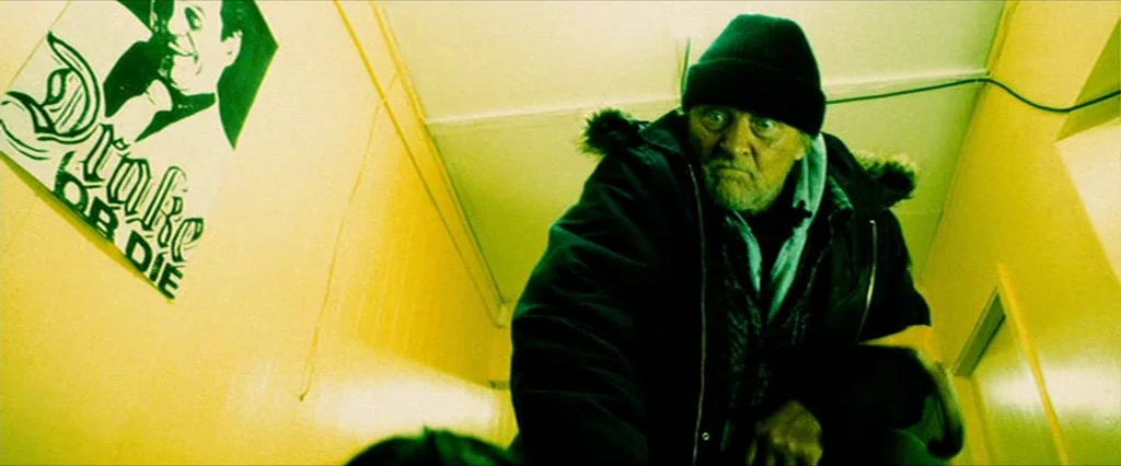 Hobo With A Shotgun (2011) movie still: medium — A narrow stairwell features bright yellow walls adorned with a framed black and white poster. An…