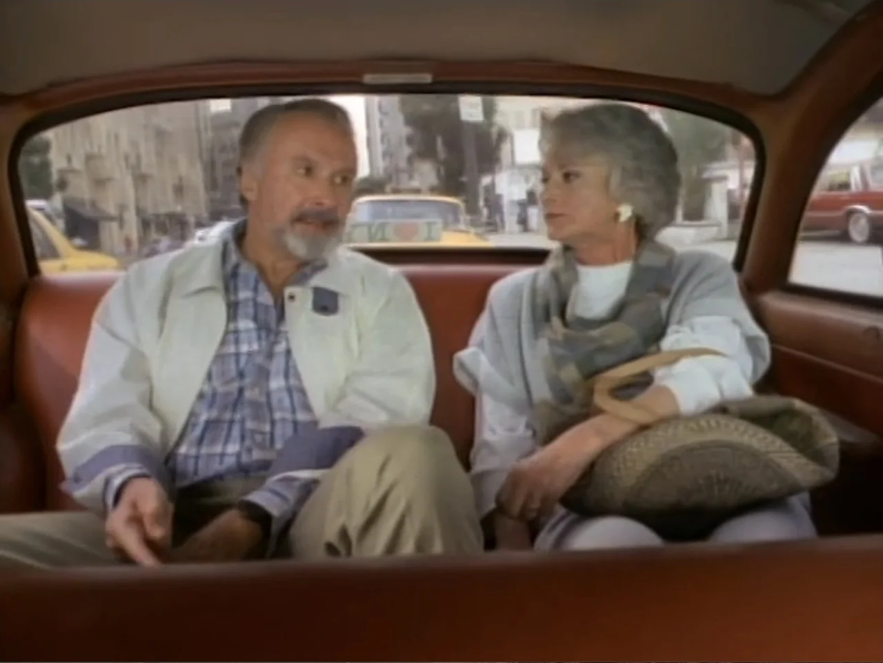 My First Love (1988) movie still: medium — The interior of a moving taxi cab with brown leather upholstery visible. Two elderly people sit on the…