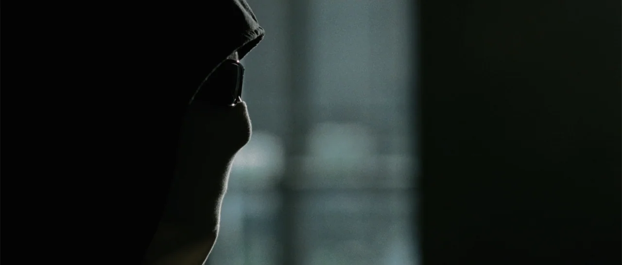 Inside Man (2006) movie still: closeup — An interior space features a dark, out-of-focus background with a light source visible through a window. A…