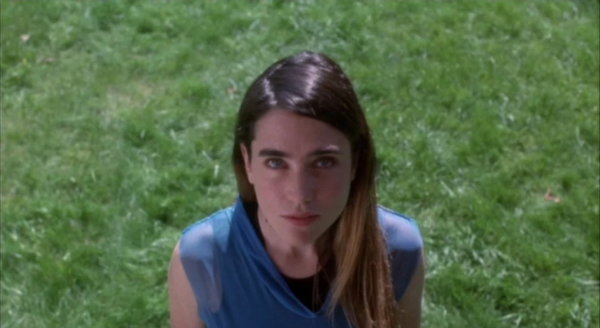 Requiem For A Dream (2000) movie still: medium — A person stands in the center of an open green grass field. The camera looks down at her while she…