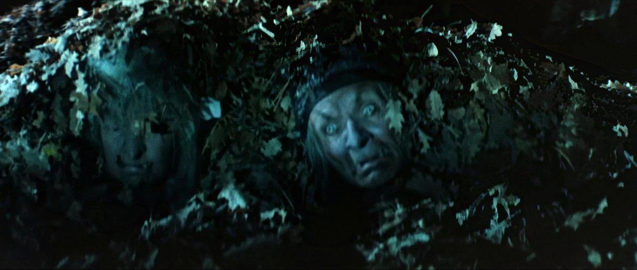 Through Fire, Water and… Brass Pipes (1968) movie still: medium — Two individuals are partially buried in a dense layer of dry brown leaves. The…