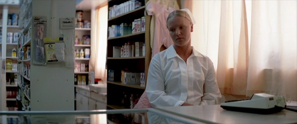 Silent Light (2007) movie still: medium — A pharmacy interior features wooden shelves stocked with various medical and personal care products. A…
