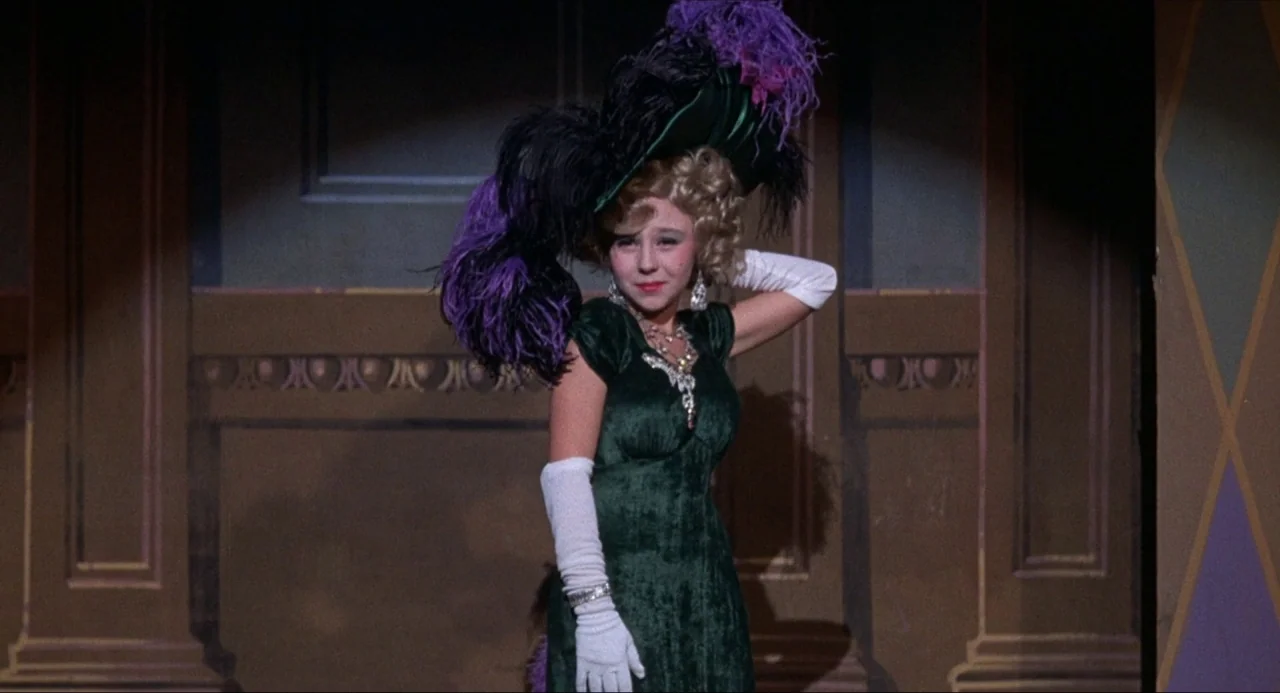What’s the Matter with Helen? (1971) movie still: medium — A painted backdrop of a vintage interior provides the setting for a performance. A young…